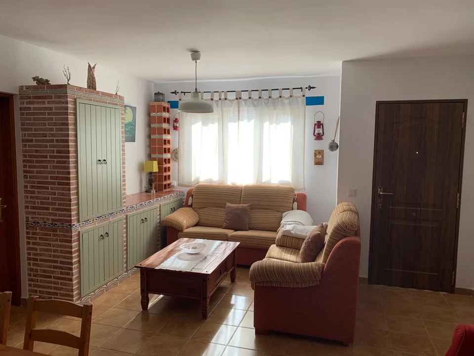 Vista del salón con sofás, mueble de obra y luz natural