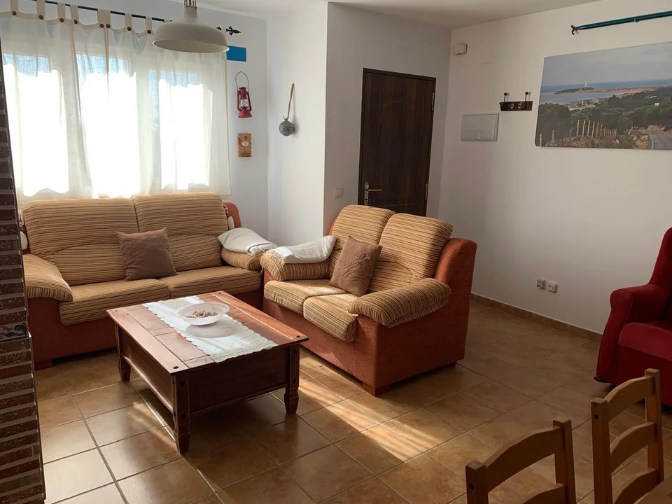 Salón de Casa Poniente con sofá, sillones y mesa de centro junto a la ventana